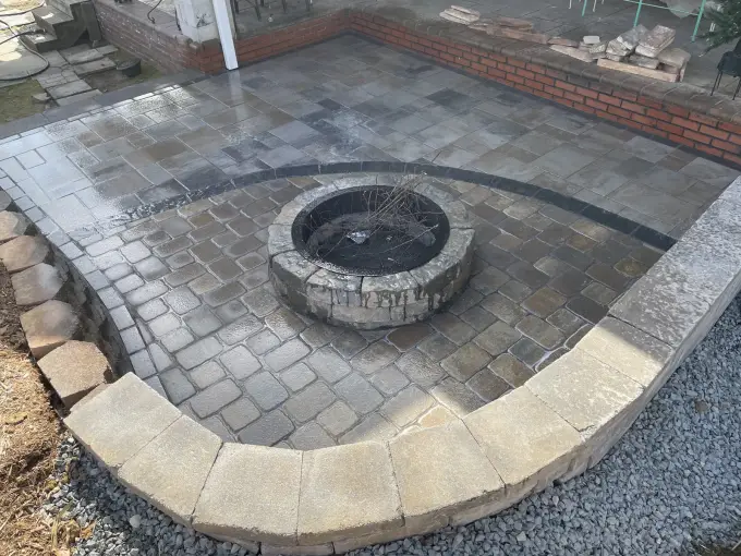 Paver patio with a sweeping curved seating wall wrapping a round paver fire pit