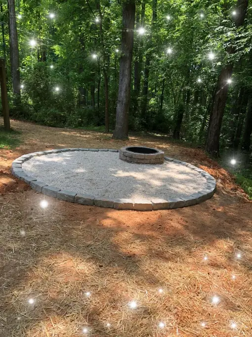 Circular paver fire pit patio nestled among the trees in a wooded backyard