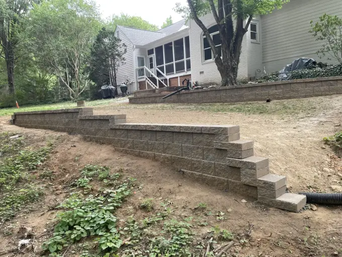 Stacked-block retaining wall with integrated steps built into a sloped backyard