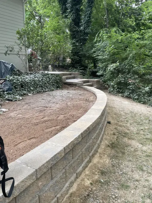 Long curved retaining wall newly built to terrace a sloped, wooded yard