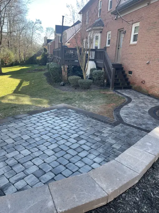Cobblestone paver walkway with a soldier-course border running beside a brick home
